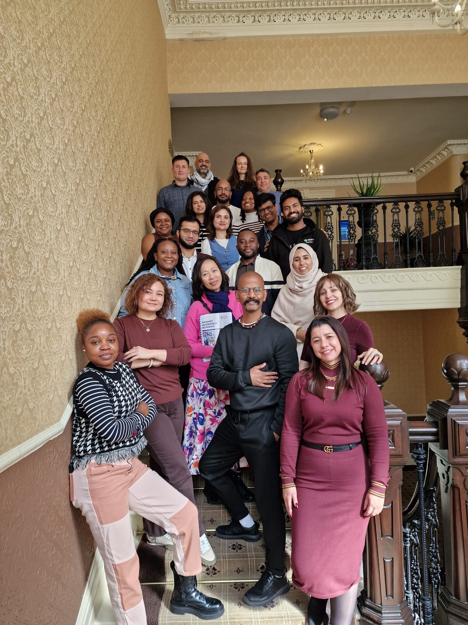 A group of people stand on a staircase smiling at the camera.