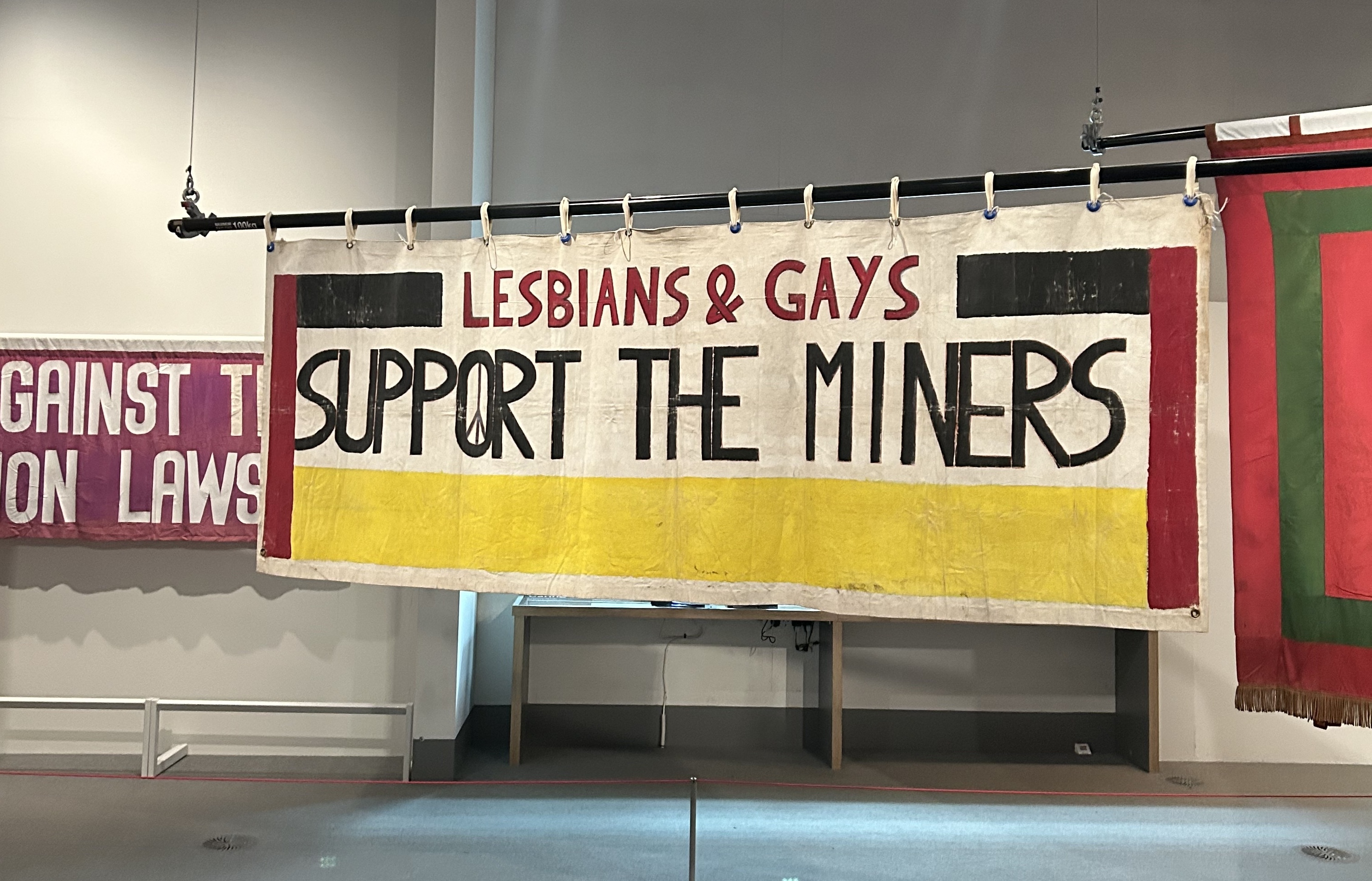 A banner hanging in the People's History Museum in Manchester, which reads, ‘Lesbians & Gays Support the Miners’.