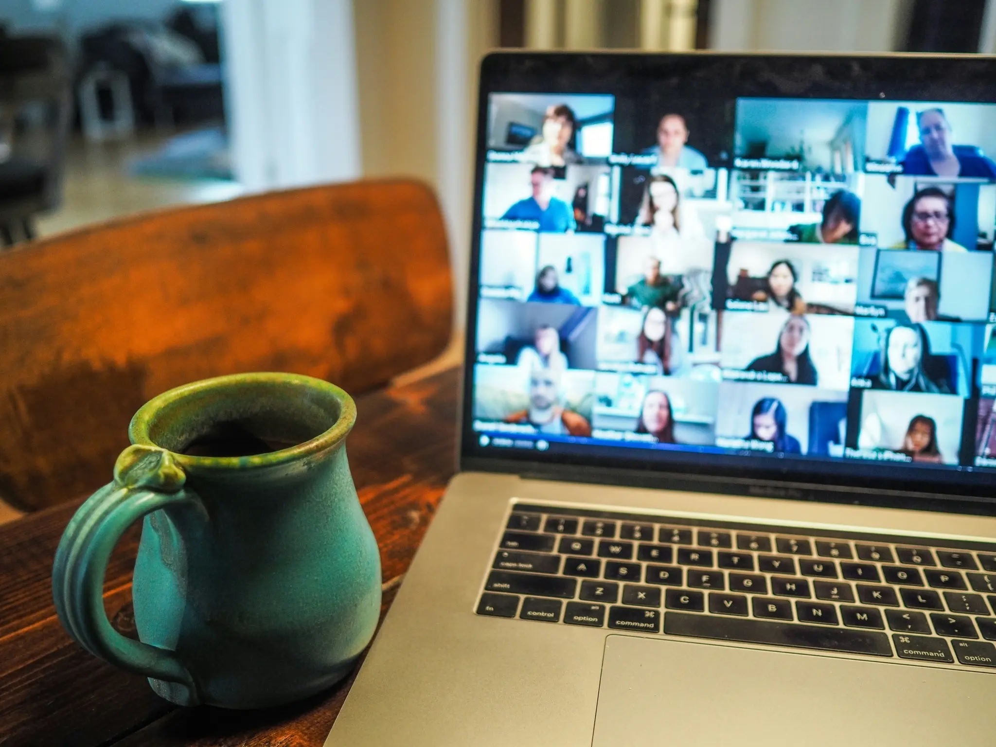 Laptop, on a table next to a mug, with a video call on screen showing multiple participants.