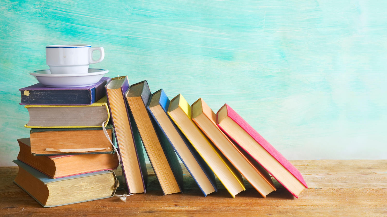 A stack of books with a cup of tea balancing on top.