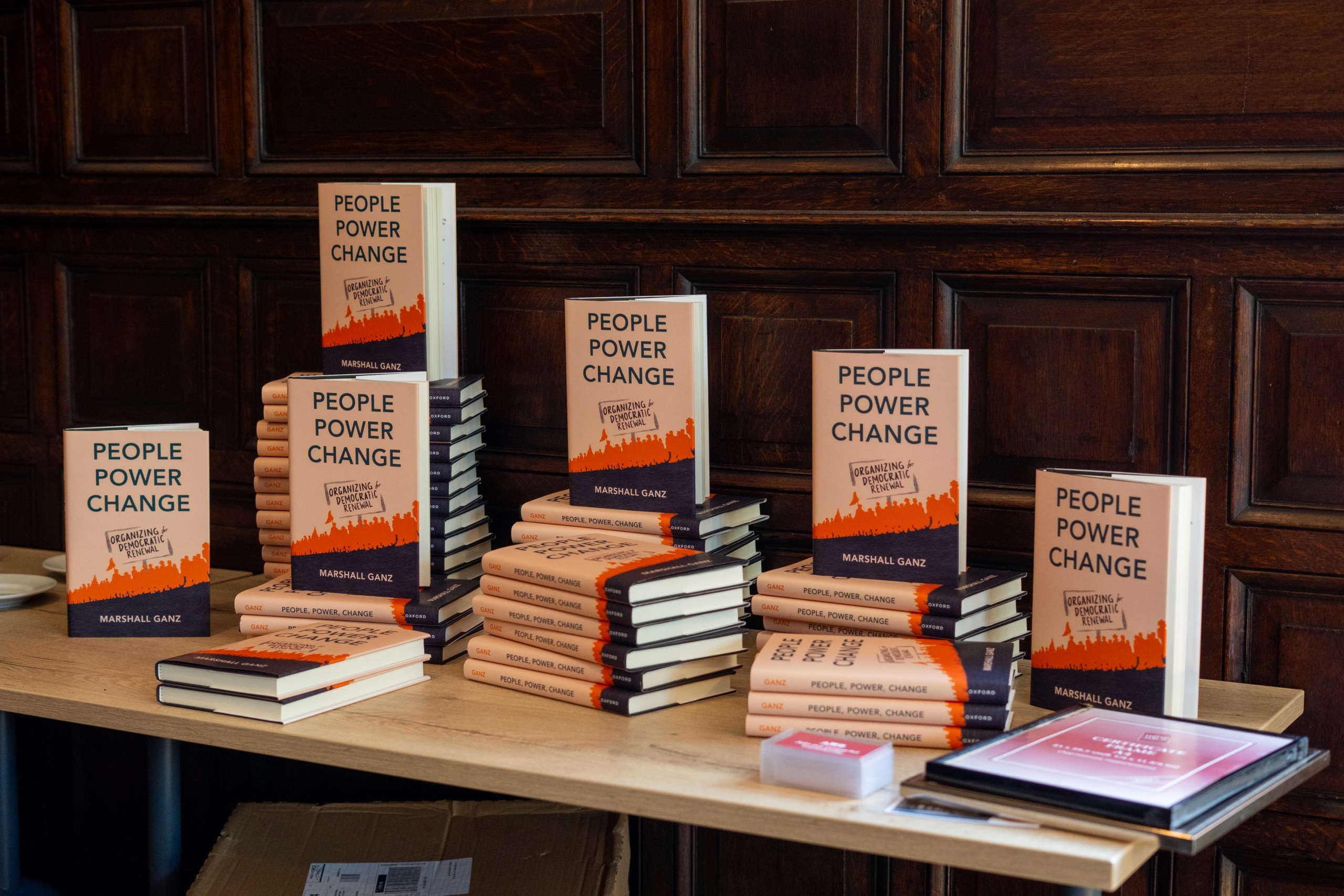 Piles of books laid out on a table with a book standing up on each pile. The books have the words, People Power Change, in large type on the front, a silhouette of people marching, and the name Marshall Ganz (the author).