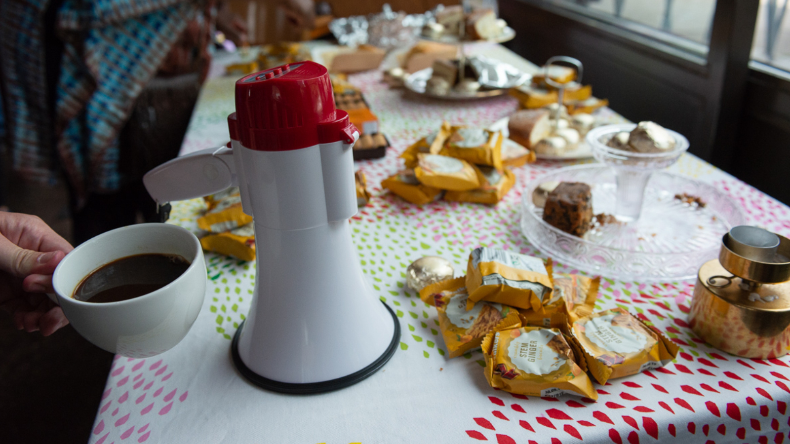 An image of a megaphone on a table with teas and biscuits.