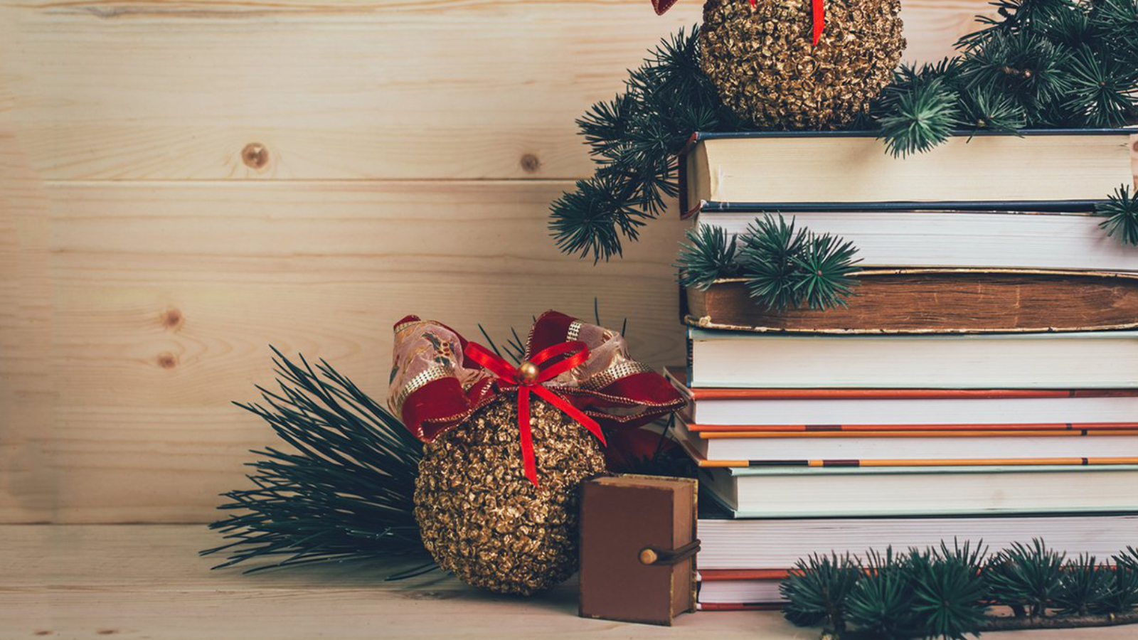 An image of a stack of books with Christmas pine branches around them.